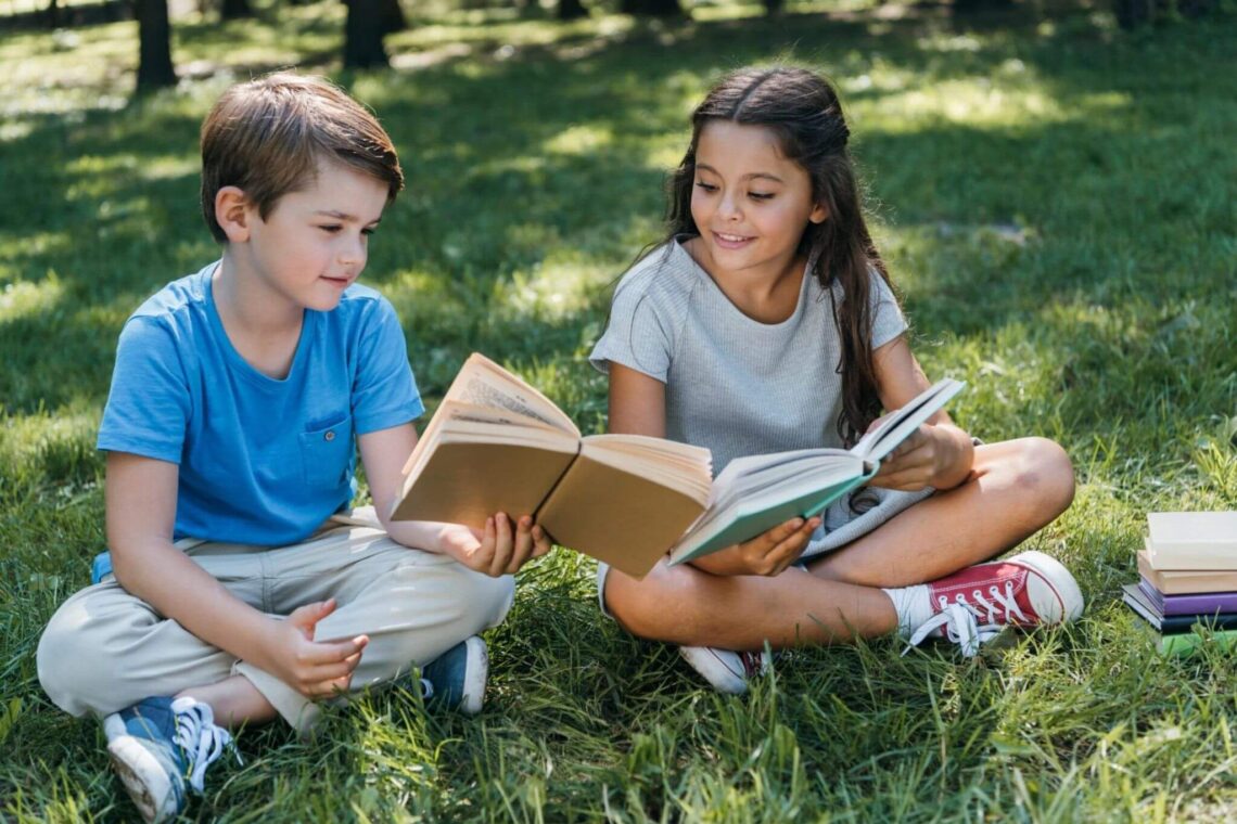2 crianças lendo no gramado. Livros infantis / Reprodução cdn.culture
