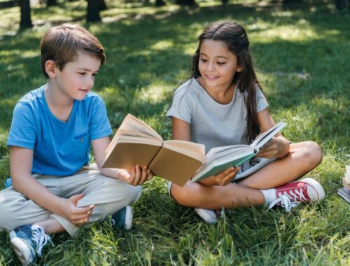 2 crianças lendo no gramado. Livros infantis / Reprodução cdn.culture