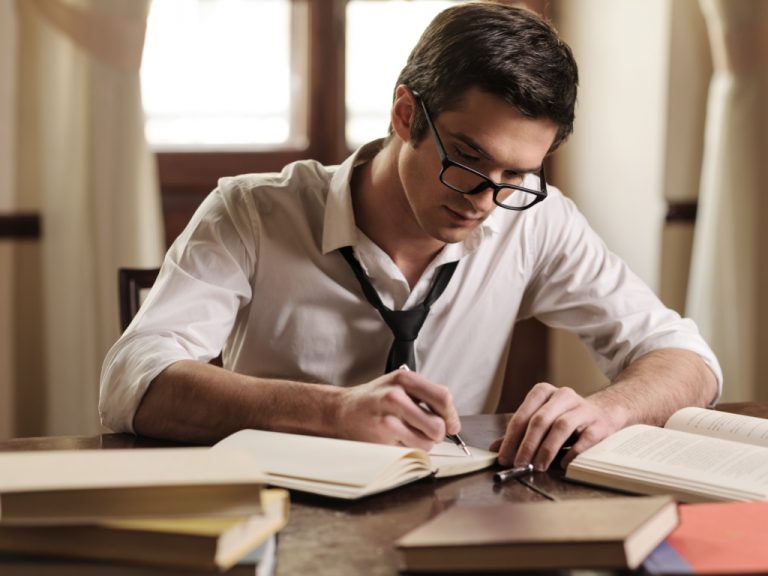 Homem sentado escrevendo livro / Reprodução pratikakkawar